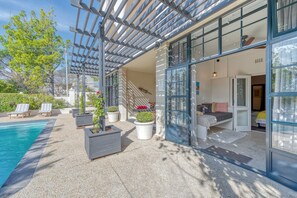 A modern outdoor area with a pool, lounge chairs, and potted plants.