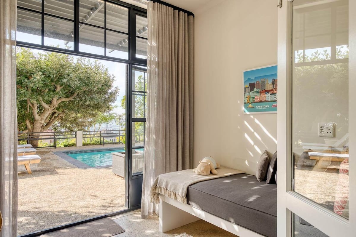A bedroom with a view of a swimming pool and a tree.