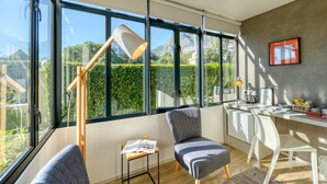 A modern kitchen with large windows, a dining area, and a reading nook with a lamp. - De Tafelberg Guesthouse (Cape Town)