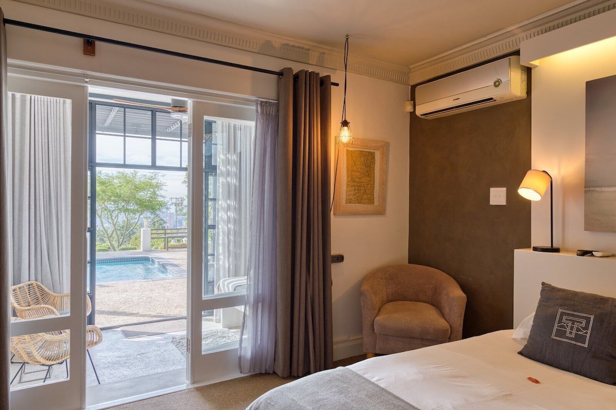 A hotel room with a bed, a chair, a desk, and a view of a swimming pool.