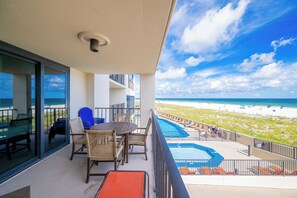 Un balcon avec vue sur la plage, une piscine et un espace salon extérieur.