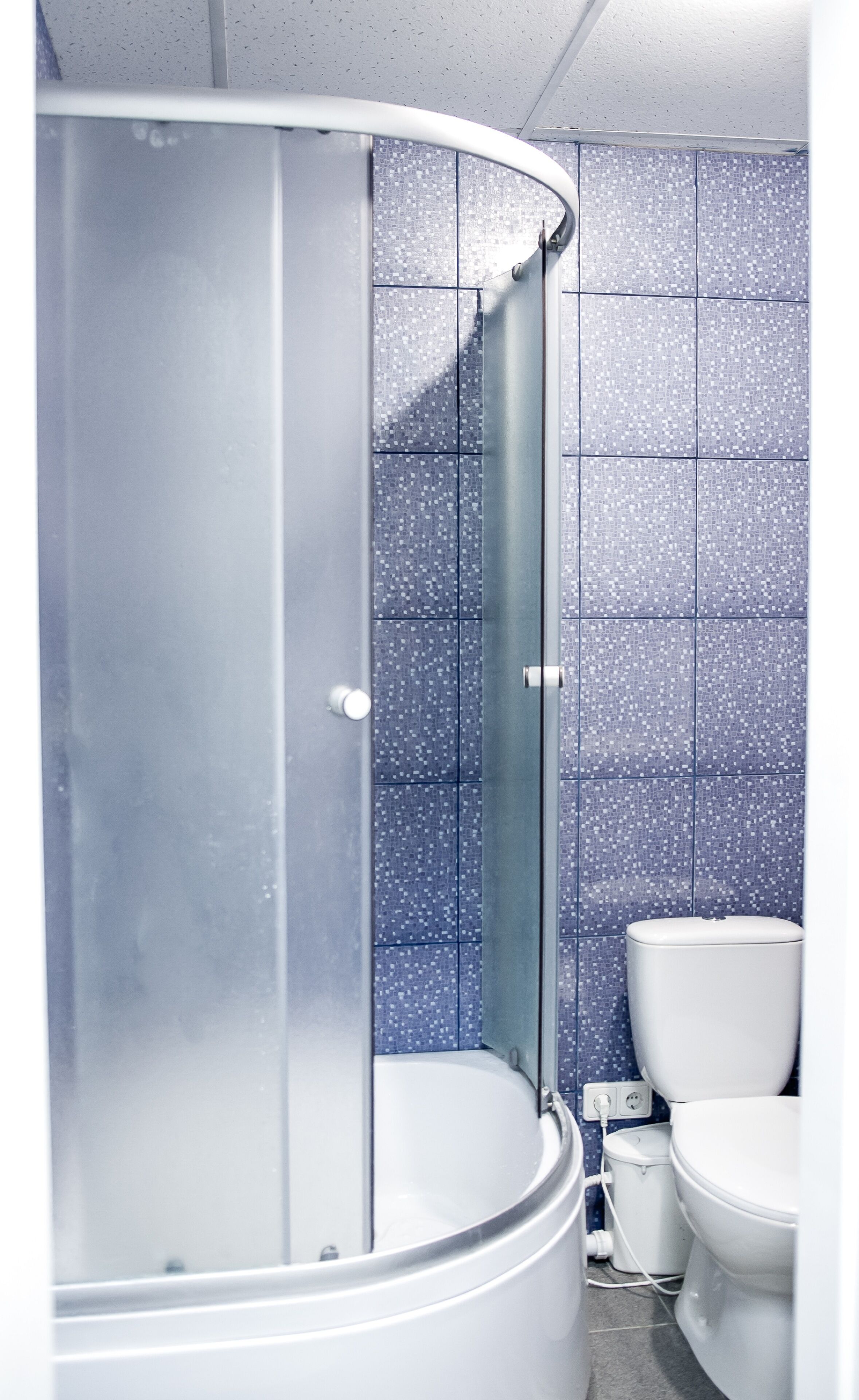 A bathroom with a shower enclosure, a toilet, and tiled walls.