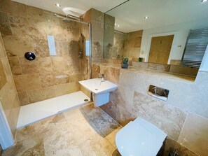 Un baño moderno con ducha a ras de suelo, lavamanos pedestal y retrete.