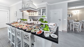 Une cuisine spacieuse dotée d’un grand îlot central, de meubles blancs et d’un coin repas avec des chaises blanches.