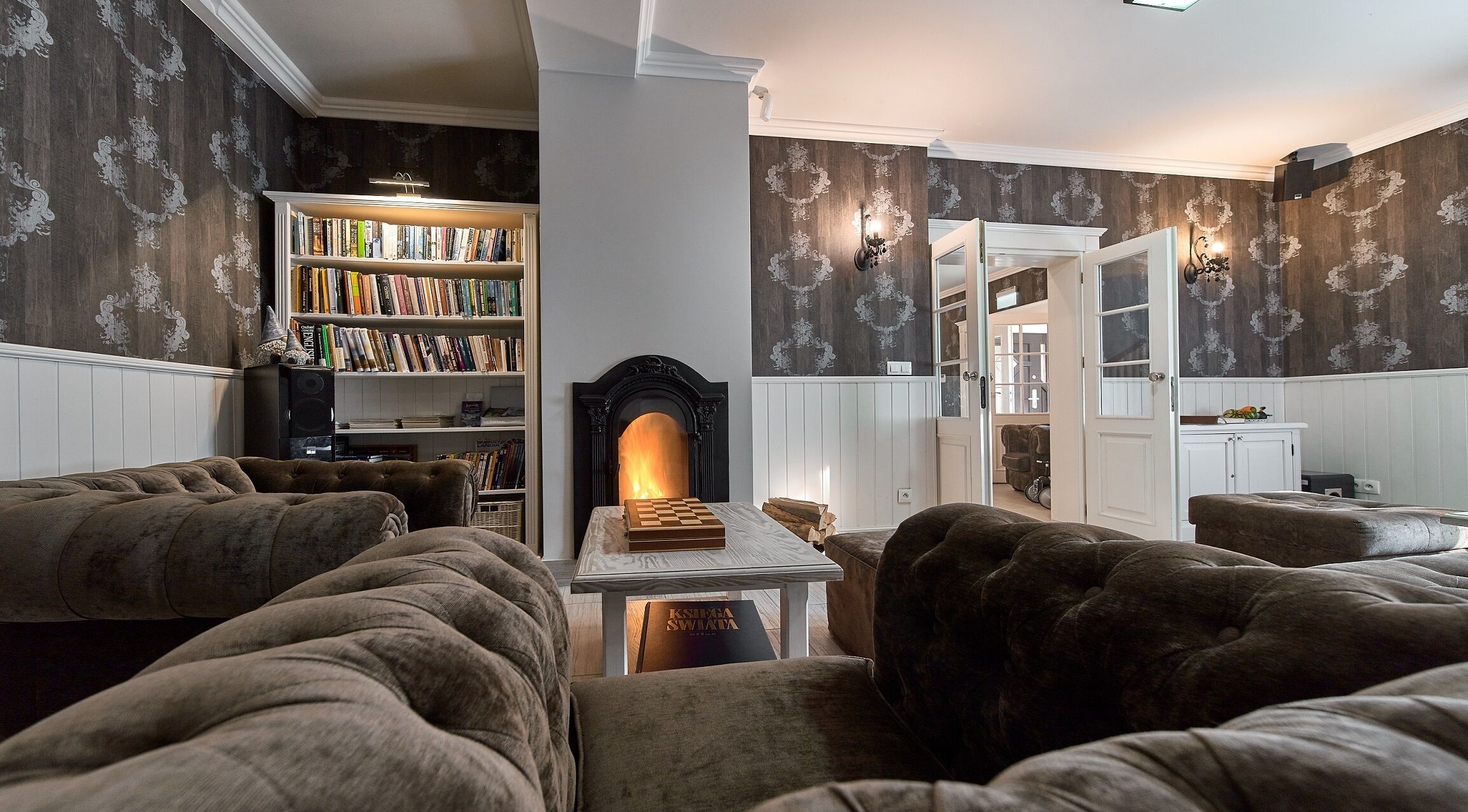 Una sala de estar acogedora con chimenea, sofás cómodos, una estantería y un comedor.