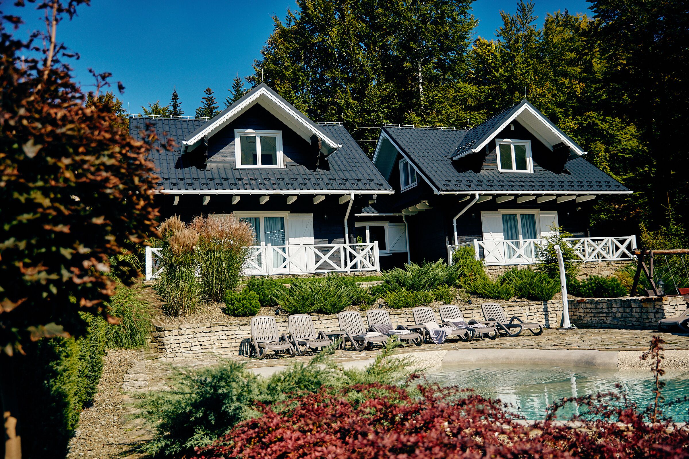 Ein zweistöckiges Haus mit Pool, umgeben von Grünflächen und einem weißen Zaun.