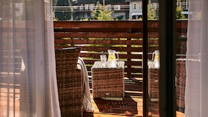 Des meubles en osier, un pichet en verre et un verre posés sur une table en bois.