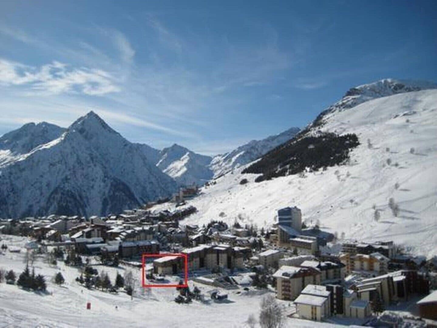 Une ville de montagne enneigée, avec des bâtiments et un sommet imposant en arrière-plan.