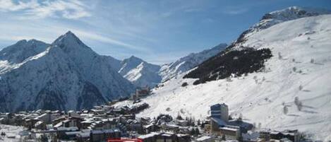 Une ville de montagne enneigée, avec des bâtiments et un sommet imposant en arrière-plan.