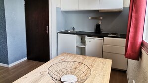 A compact kitchen with white cabinets, a black countertop, and a small refrigerator. - Apartment in Les 2 Alpes. Snow front. 4 people max. (Mont-de-Lans)
