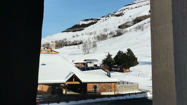 A view of a snowy mountain landscape with buildings and a parking area. - Apartment in Les 2 Alpes. Snow front. 4 people max. (Mont-de-Lans)