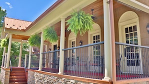 A covered porch with columns, a red carpet, and hanging plants. - The Hygrade Inn (Emporium)