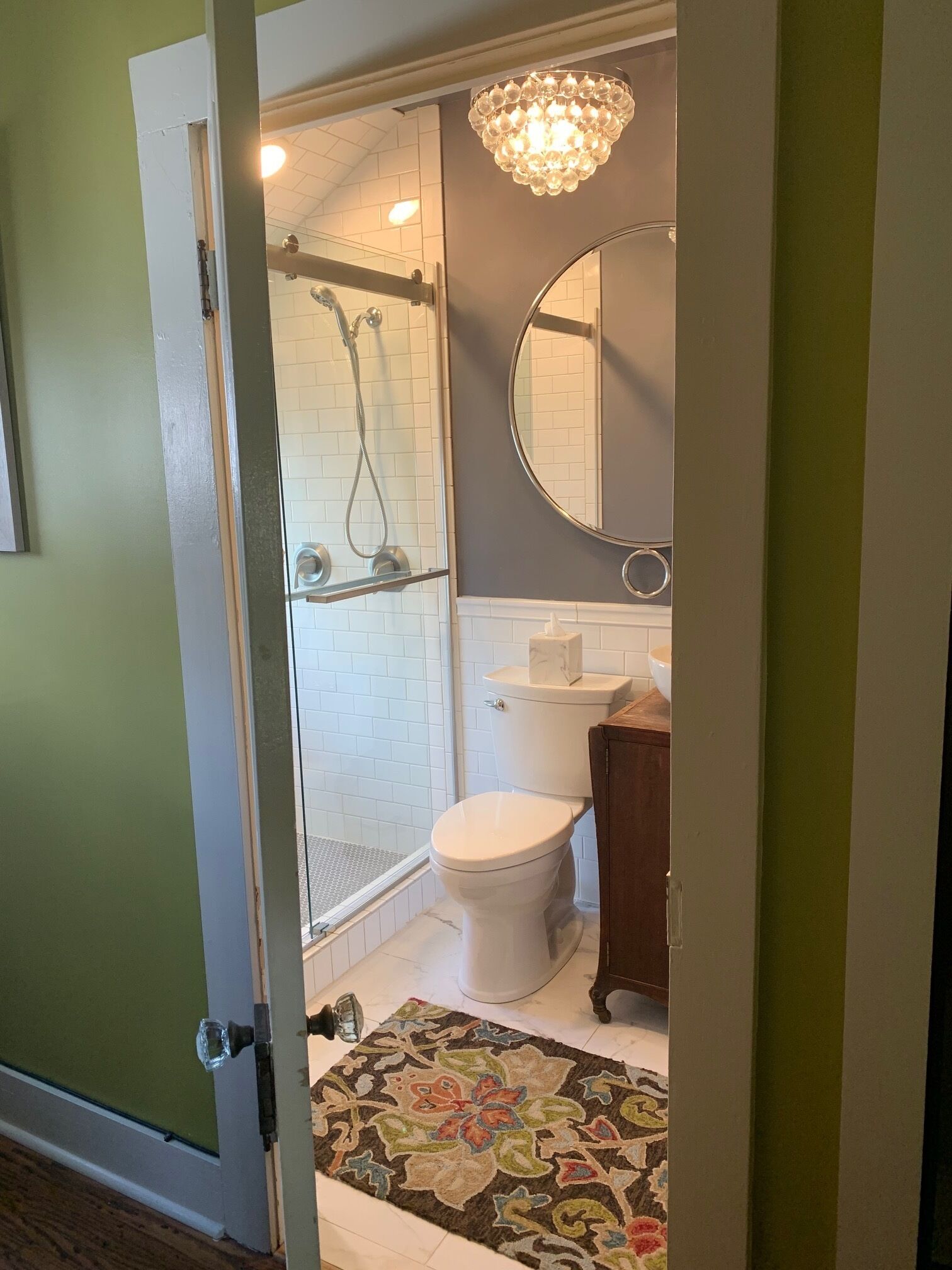 A bathroom with a shower, toilet, and a mirror.