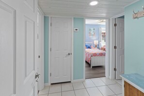 A hallway leading to a bedroom with a bed, a nightstand, and a lamp.