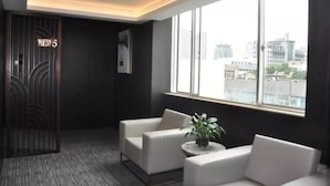 Une chambre d’hôtel moderne avec une grande fenêtre, un mur de couleur sombre et un canapé blanc.