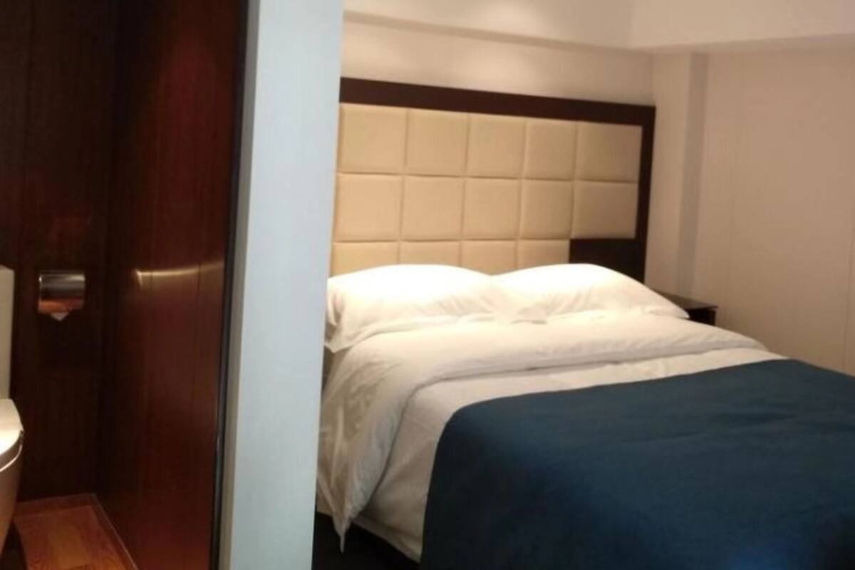 Een hotelkamer met een bed, een houten deur en een witte muur.