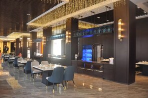 Un restaurante moderno con una barra alargada, sillas azules y una pantalla de televisión.