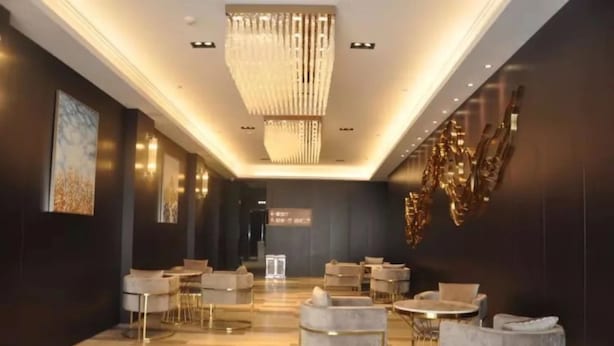 Un hall d’hôtel moderne agrémenté d’un lustre, de coins salon et d’œuvres d’art aux murs.