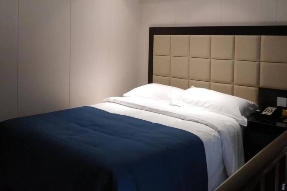 Een hotelkamer met een bed, nachtkastje en een telefoon aan de muur.