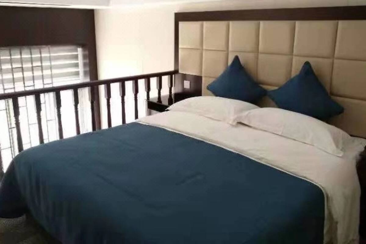 Een hotelkamer met een bed, hoofdbord en een raam met luxaflex.
