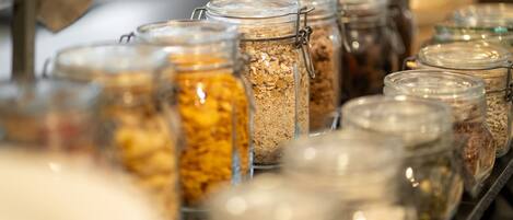 Una hilera de frascos de vidrio con cierres metálicos, que contienen diversos alimentos.