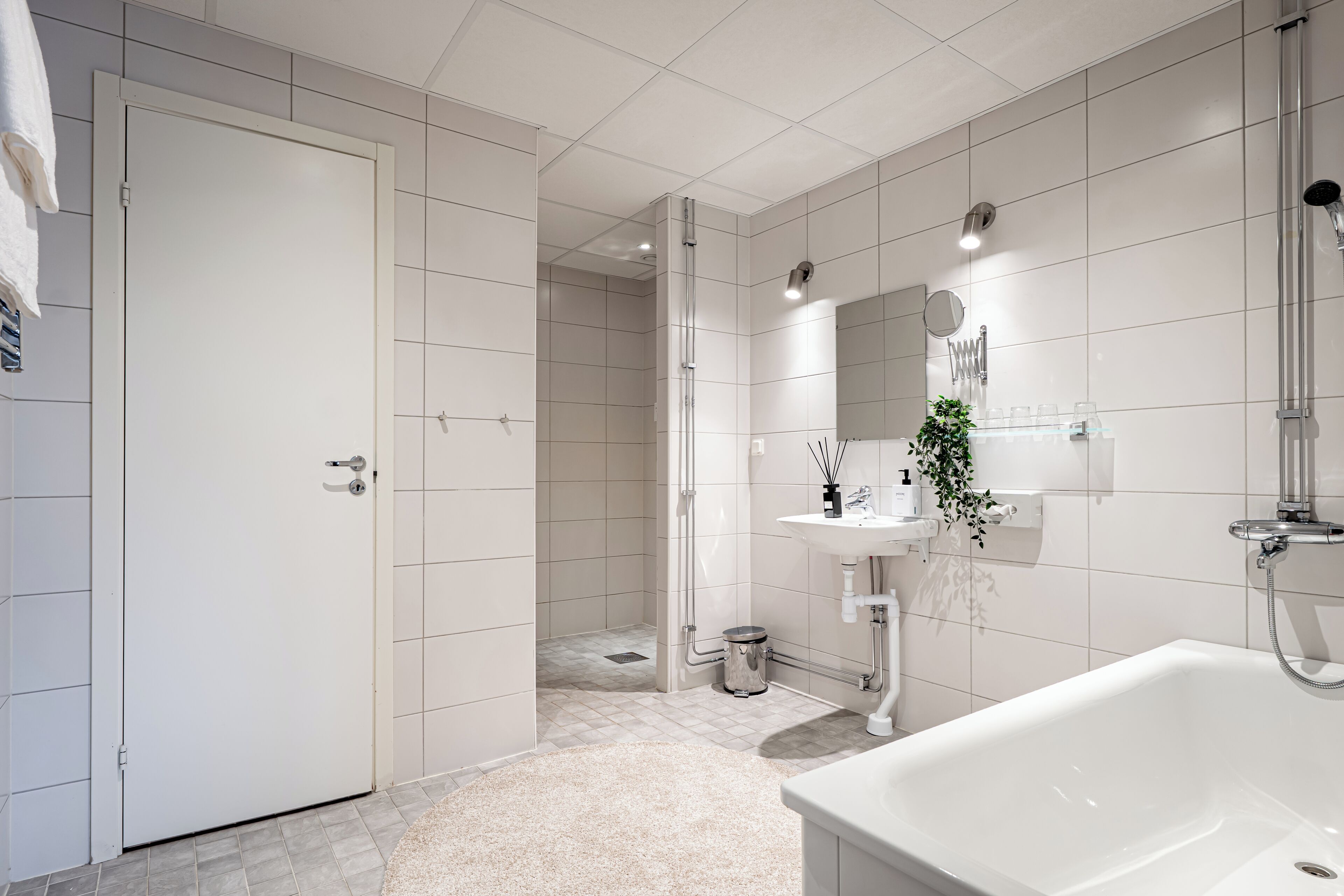 A modern bathroom with a white sink, a mirror, and a shower area.