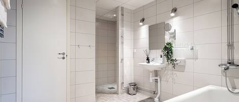 A modern bathroom with a white sink, a mirror, and a shower area.