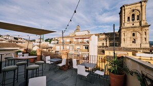 An outdoor terrace with tables and chairs, overlooking a historic building with a bell tower. - Toc Hostel Granada (Granada)