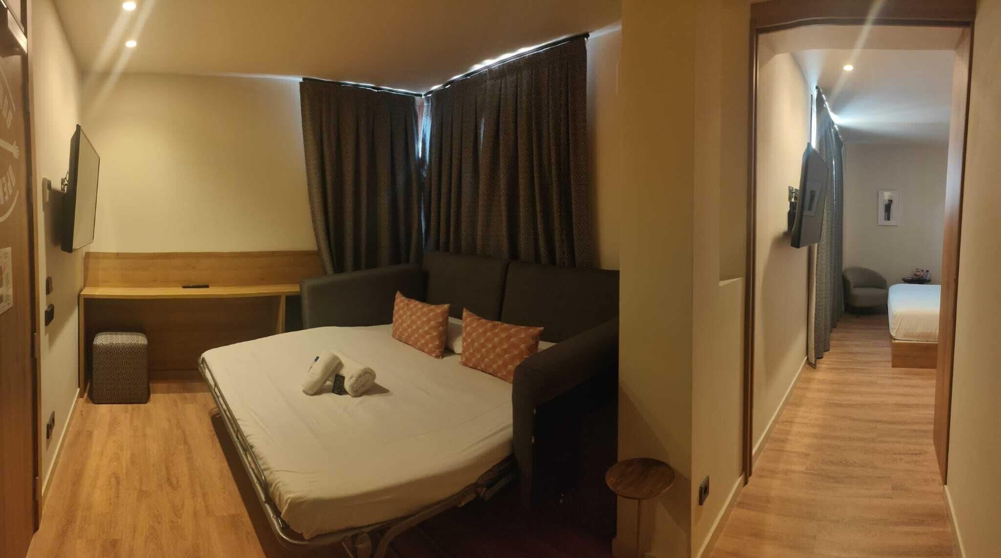 Ein kleines Hotelzimmer mit Bett, Nachttisch, Stuhl und Kleiderschrank.