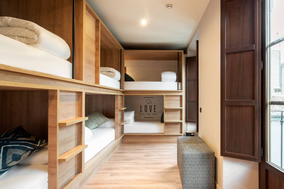 A compact, multi-level bedroom with bunk beds, built-in shelves, and a cozy seating area.