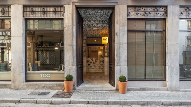 A hotel entrance with a modern design, including a patterned ceiling and a sign indicating it is a TOC hostel/suites. - Toc Hostel Granada (Granada)