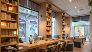 A cozy reading area with bookshelves, a long table, and comfortable seating. - Toc Hostel Granada (Granada)