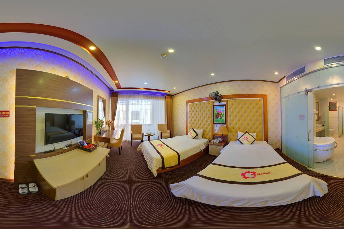 Habitación de hotel con techo curvo, dos camas, un televisor, un escritorio y un baño.