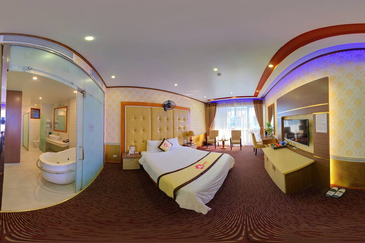 Una habitación de hotel con una cama grande, un área de descanso, un escritorio y un baño.