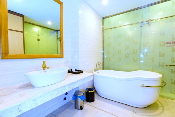 Une salle de bain dotée d’un grand miroir, de deux lavabos, d’une baignoire et d’un espace douche.