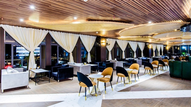 A modern restaurant with a wooden ceiling, large windows, and a mix of seating styles including sofas and chairs. - Hoa Dao Hotel (Hoa Binh)