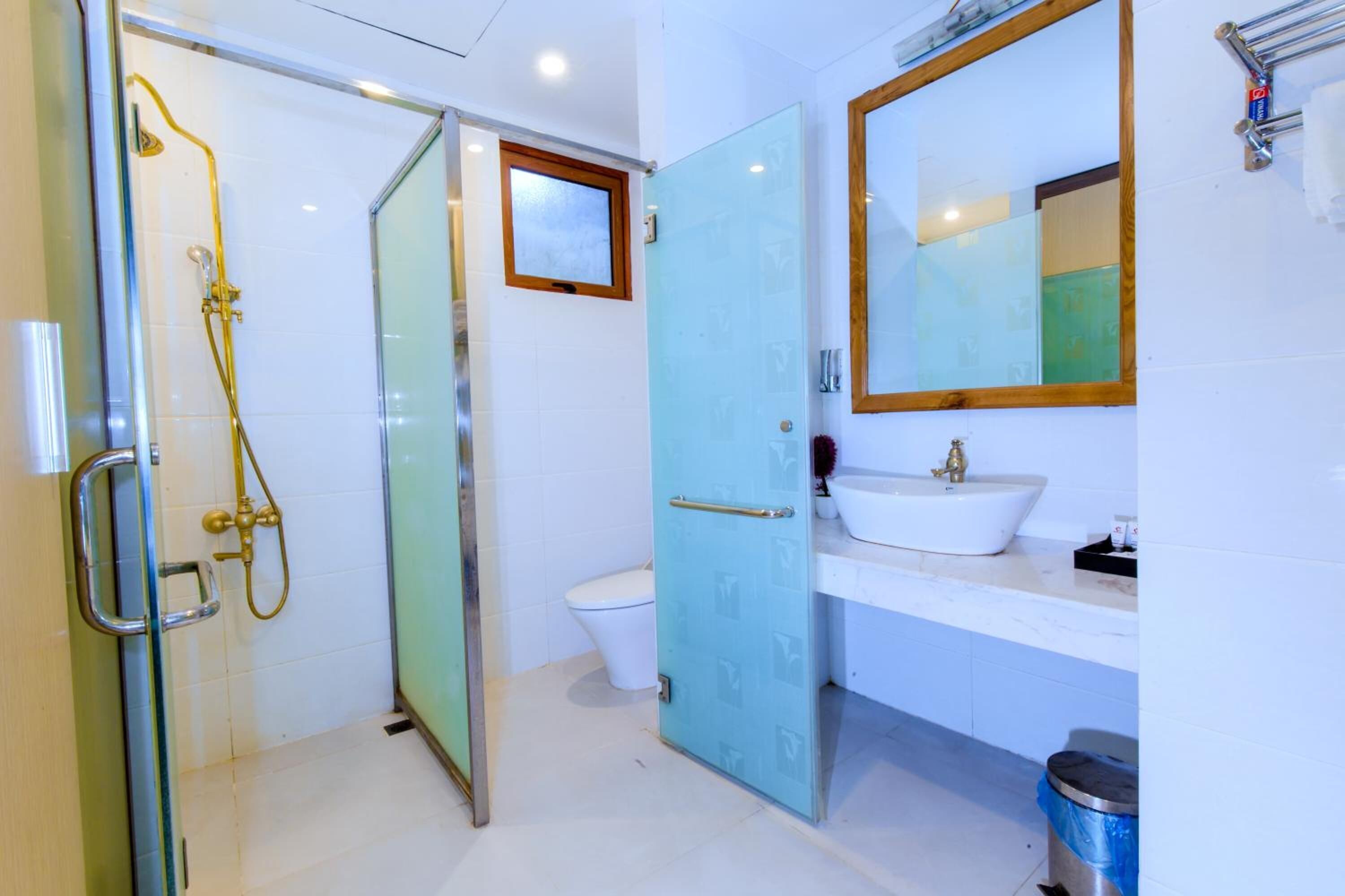 Un baño con cabina de ducha de vidrio, un lavabo blanco y un espejo sobre él.