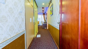 A hotel hallway with patterned wallpaper, a carpeted floor, and a wooden door. - Hoa Dao Hotel (Hoa Binh)
