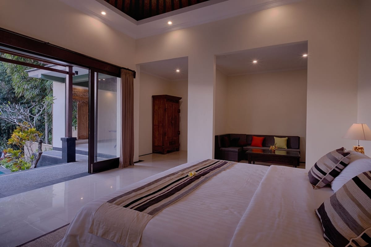 A modern hotel room with a large bed, a seating area, and a view of the outdoors.
