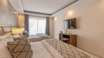 A hotel room with two beds, a desk, a chair, a TV, and a window with curtains.