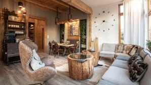 Un salon chaleureux avec une table à manger en bois, une table basse ronde et un canapé agrémenté de coussins à motifs.