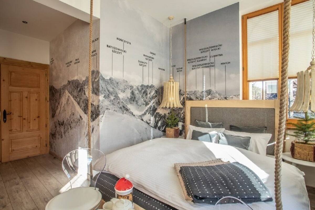 Een slaapkamer met een bed, een houten deur, een raam en een muur met een bergdecor.