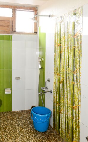 A bathroom with a shower, a bucket, and a window. - silver brook resorts (Shillong)