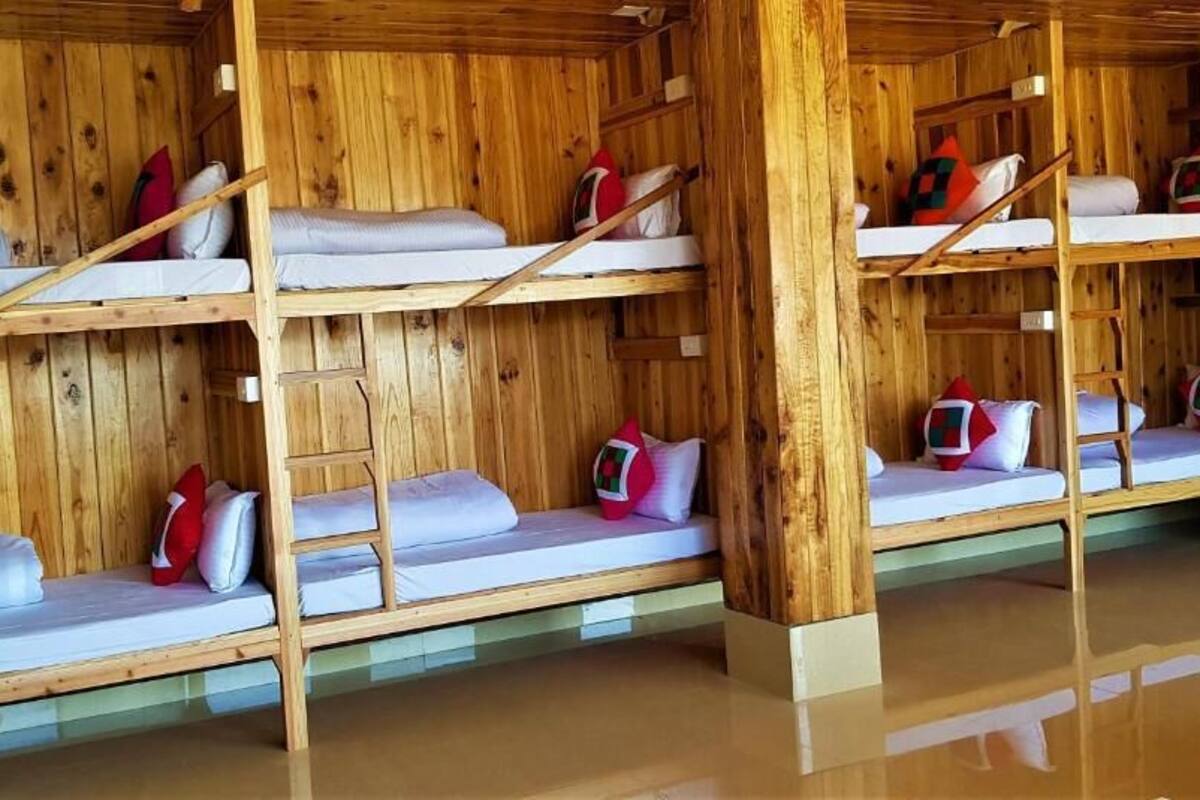 A wooden cabin with bunk beds, each with pillows and blankets.