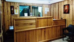 A reception desk with wooden paneling, a black chair, and informational signs.