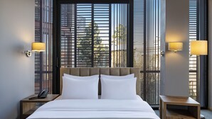 A hotel room with a large bed, two bedside tables, a telephone, and a window with blinds. - BARNOVI BOUTIQUE HOTEL (Tbilisi)