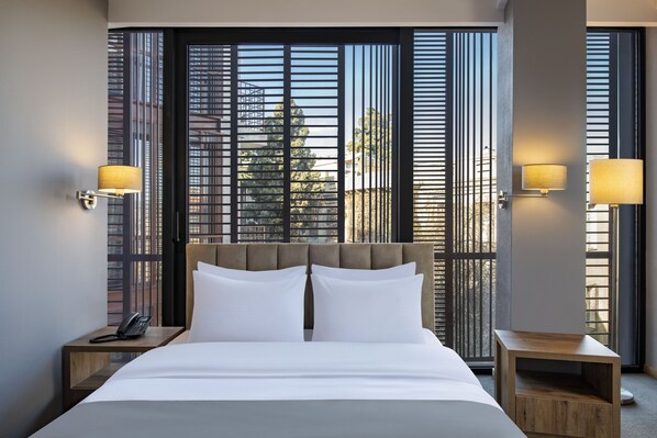 A hotel room with a large bed, two bedside tables, a telephone, and a window with blinds. - BARNOVI BOUTIQUE HOTEL (Tbilisi)