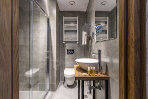 A modern bathroom with a glass shower enclosure, a white toilet, and a wooden vanity with a large sink. - BARNOVI BOUTIQUE HOTEL (Tbilisi)