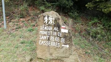 Un cartel de piedra con texto en varios idiomas, rodeado de follaje natural.