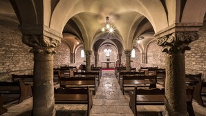 A church interior with stone columns, wooden pews, and a stone floor. - Hotel J. Balmes Vic (Vic)